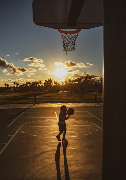 Un garçon souriant et mignon joue au basket-ball avec des enfants actifs qui profitent d'un jeu en plein air avec un sport de basket-ball pour les enfants