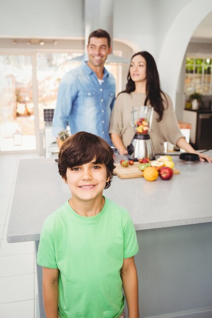 Garçon souriant avec des parents préparant du jus de fruits