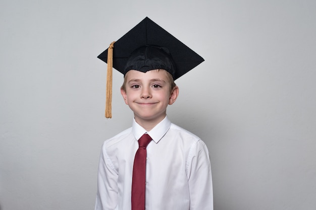 Garçon souriant portant un chapeau d'étudiant. Collège, concept de lycée. portrait demi-longueur.