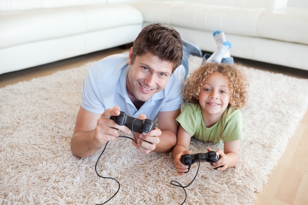 Garçon souriant et son père jouant à des jeux vidéo