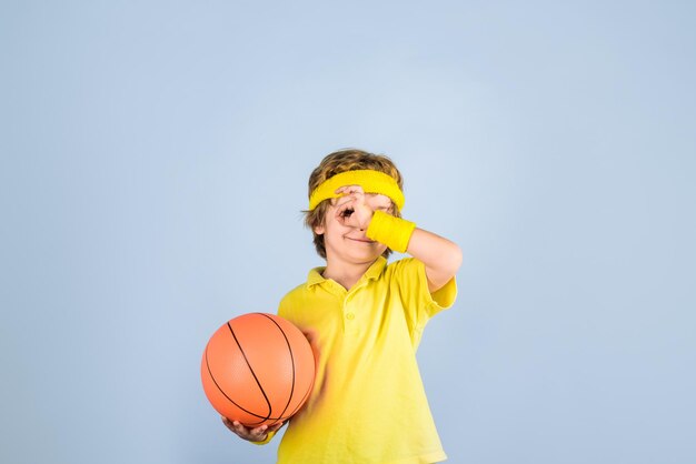 Garçon de sport de basket-ball de style de vie actif avec le garçon de sport de ballon de basket-ball montre le signe ok l'enfant tient le ballon