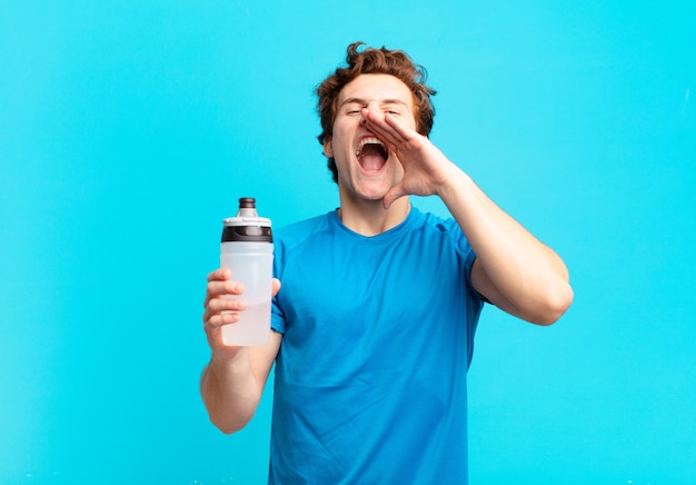 Garçon de sport se sentant heureux, excité et positif, donnant un grand cri avec les mains à côté de la bouche, appelant. concept de boisson énergisante