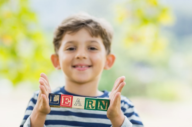 Garçon tenant des blocs dans le parc qui lit apprendre