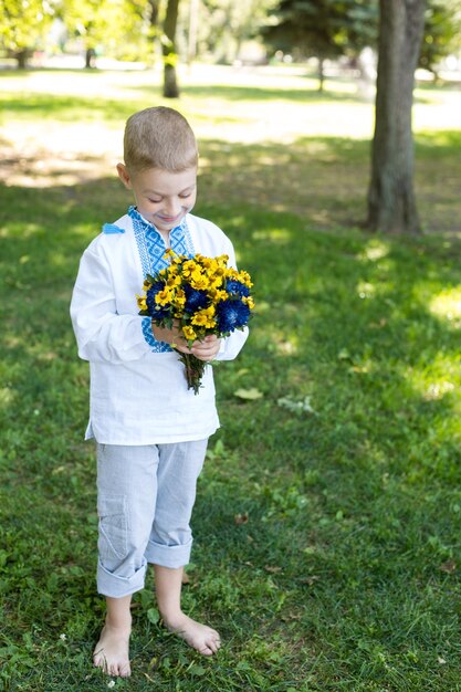 Un garçon tenant un bouquet de fleurs jaunes et bleues