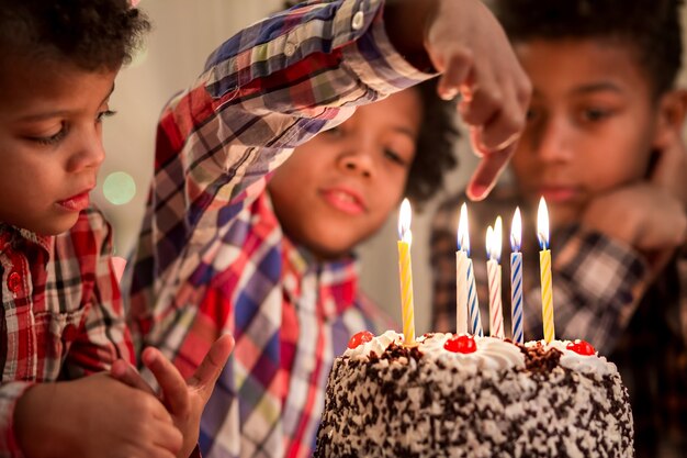 Garçon tenant le doigt sur une bougie enfant jouant avec des gâteaux bougies ne vous brûlez pas assez vieux pour essayer ceci