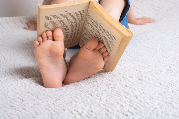 Garçon tenant un livre sur les pieds comme concept de la journée mondiale du livre