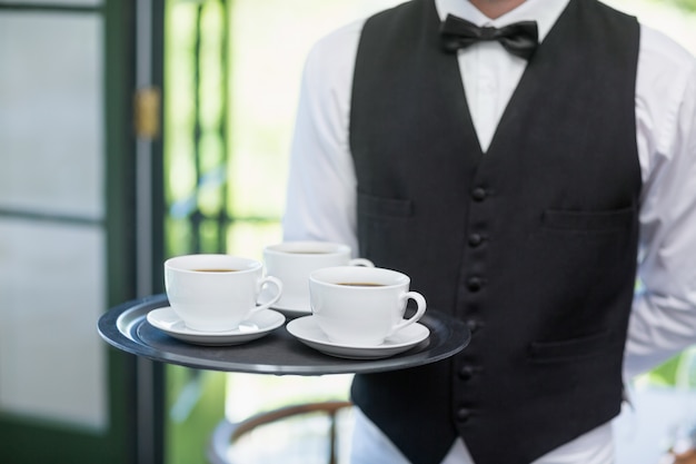 Garçon tenant un plateau avec des tasses à café