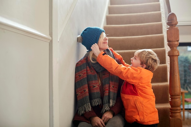 Un garçon tirant un chapeau sur les yeux de sa mère