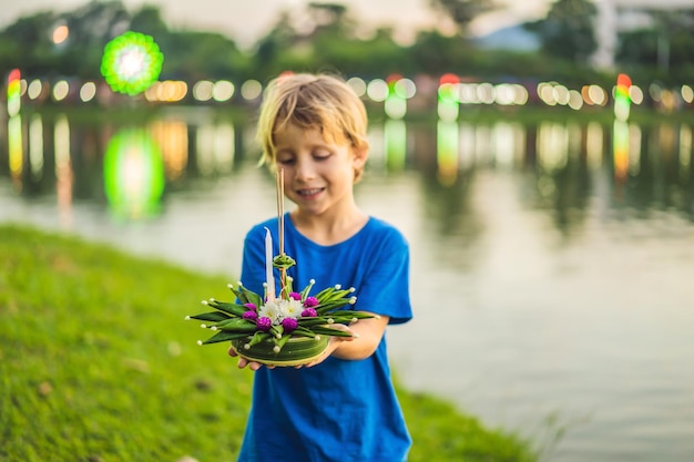 Garçon touriste tient le loy krathong dans ses mains et s'apprête à le lancer dans l'eau loy