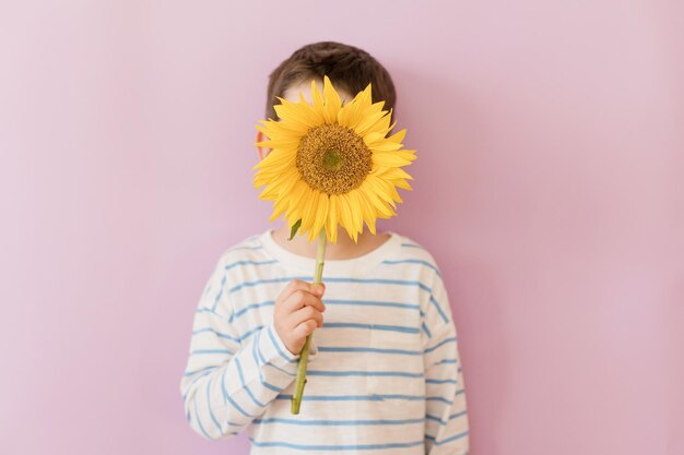 Garçon avec tournesol sur fond rose