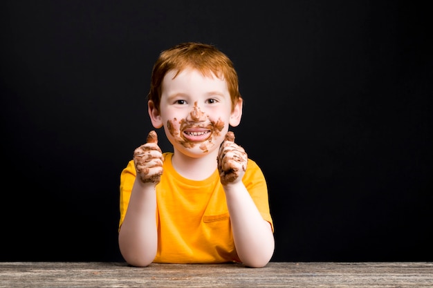 Garçon tout souillé de chocolat au lait fondant avec du sucre