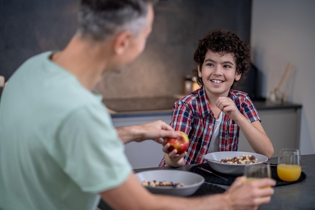 Garçon traitant le père avec une pomme assis à table