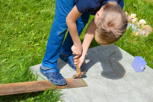 Un garçon travaille dans le jardin. Atelier pour enfants à l'extérieur