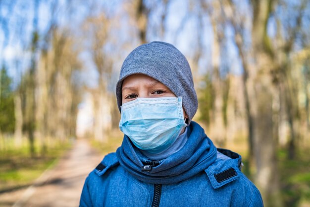 Garçon triste dans un masque médical protecteur extérieur