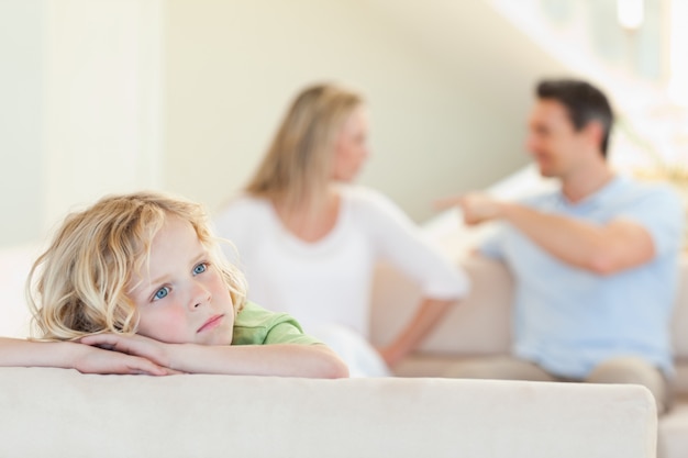 Garçon triste avec des parents qui se battent derrière lui