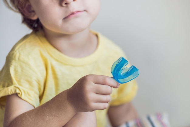 Un garçon de trois ans montre un entraîneur myofonctionnel. Aide à égaliser les dents en croissance et à corriger la morsure, à développer l'habitude de respirer par la bouche. Corrige la position de la langue.