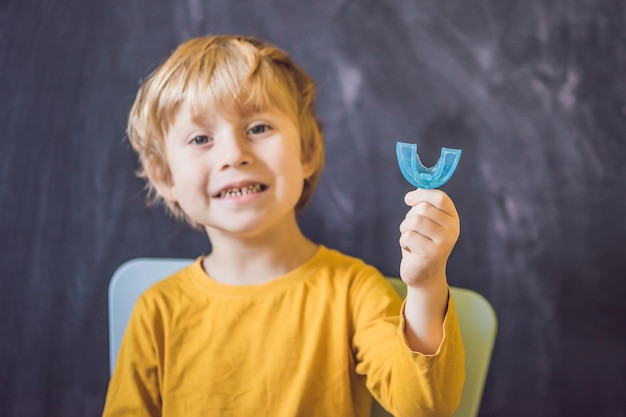 Un garçon de trois ans montre un entraîneur myofonctionnel. Aide à égaliser les dents en croissance et à corriger la morsure, à développer l'habitude de respirer par la bouche. Corrige la position de la langue