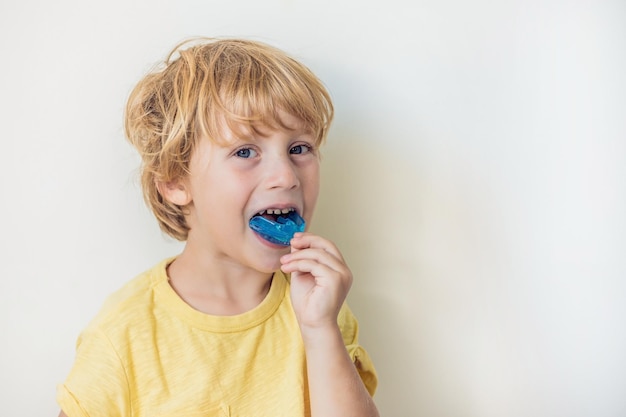 Un garçon de trois ans montre un entraîneur myofonctionnel pour éclairer l'habitude de respirer par la bouche. Aide à égaliser les dents en croissance et à corriger la morsure. Corrige la position de la langue