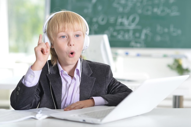 Garçon en uniforme scolaire avec casque et ordinateur portable