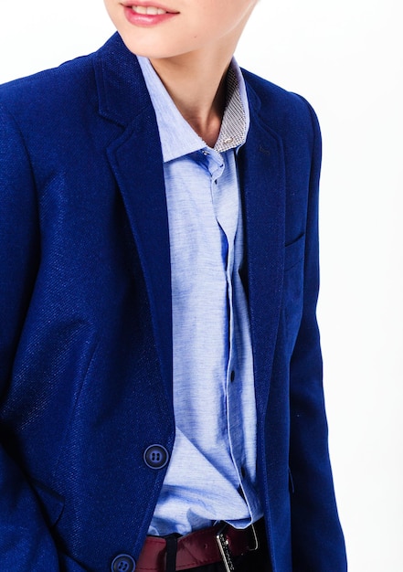 Garçon en uniforme scolaire sur fond blanc Le garçon montre une veste bleue Photo verticale