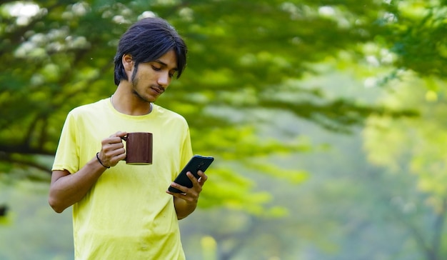 Garçon utilisant un téléphone portable le matin avec une tasse de café à la ferme