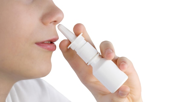 Un garçon utilise un spray nasal isolé. Adolescent utilisant un spray nasal en gros plan, espace de copie