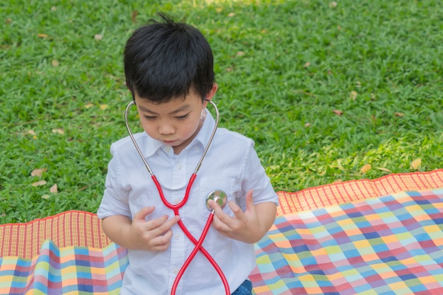 Garçon utilise des stéthoscopes et se sent heureux dans le parc du jardin.