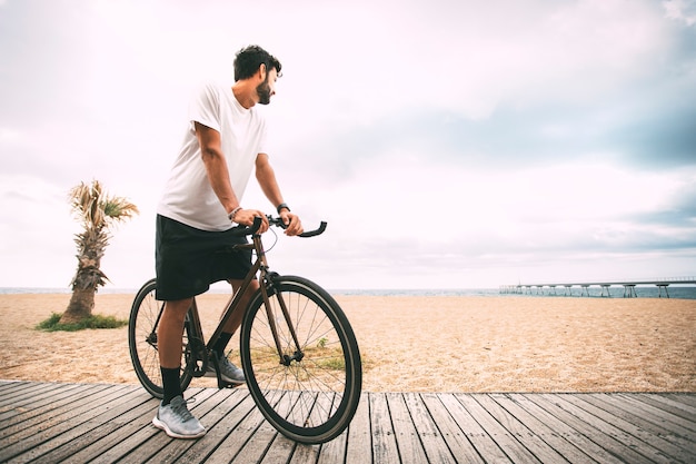 Garçon à vélo sur une passerelle en bois sur la plage en regardant la mer Espace de copie sport Style de vie