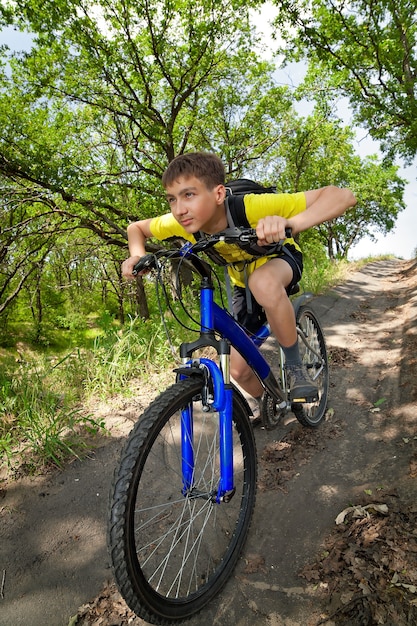 Garçon sur un vélo voyageant dans la forêt