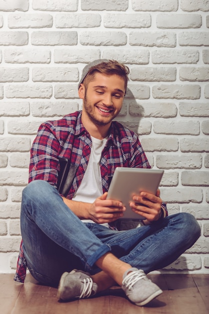 Garçon en vêtements décontractés et casquette utilise une tablette numérique.