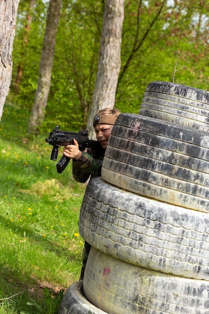 Garçon vêtu de camouflage jouant au laser tag dans une aire de jeux forestière spéciale