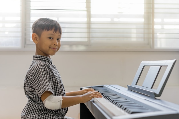 Un garçons asiatiques aux mains blessées jouant du piano