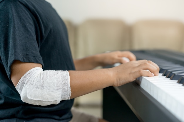 Un garçons asiatiques aux mains blessées jouent du piano