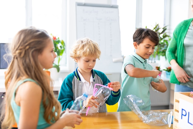 Garçons et fille. Deux beaux garçons et une fille séduisante triant les déchets à l'école lors de la leçon d'écologie