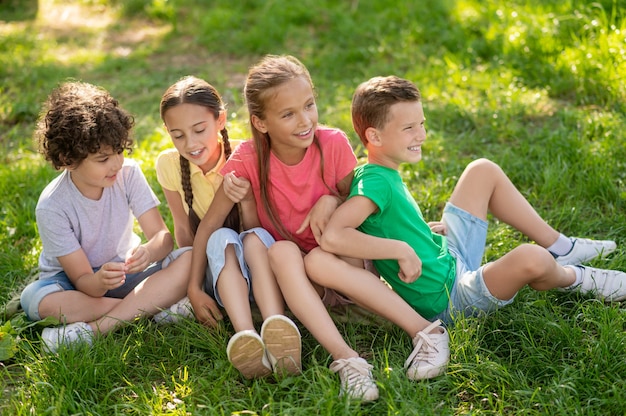 Garçons et filles souriants assis sur une pelouse verte