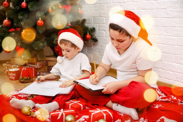 Des garçons partagent leurs rêves la veille de Noël près de l'arbre de Noël