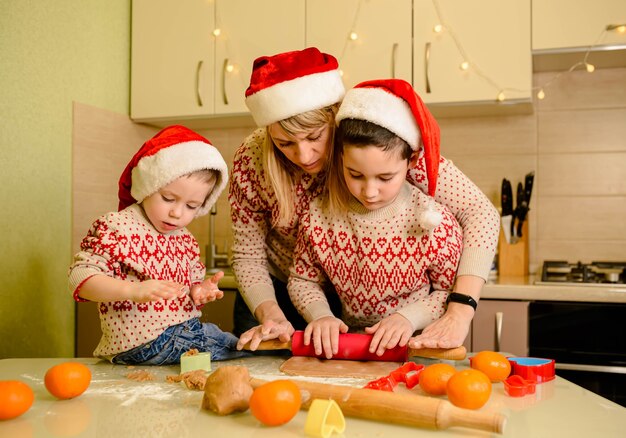 Garçons souriants et mère préparant des biscuits de Noël à la maison