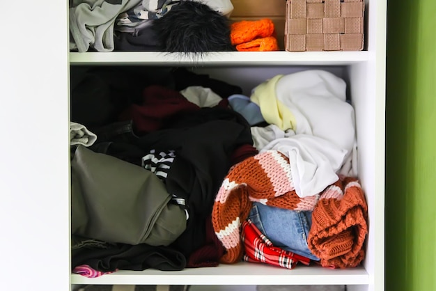 Garde-robe à la maison avec des vêtements différents. Petite organisation de l'espace. Le contraste de l'ordre et du désordre. Boîtes de rangement verticales