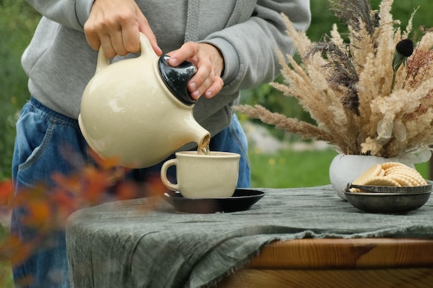 Garder au chaud le thé d'automne Ambiance d'automne Mains féminines versant du thé dans une tasse buvant du thé à l'extérieur