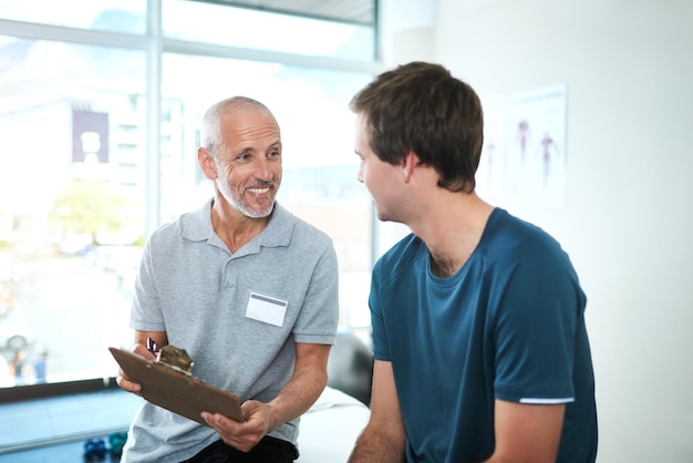 Garder un dossier complet de la santé de ses patients Photo recadrée d'un beau physiothérapeute masculin mature ayant une consultation avec un patient