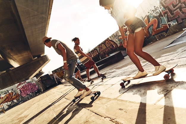 Garder leur équilibre. Groupe de jeunes faisant de la planche à roulettes tout en traînant au skate park en plein air