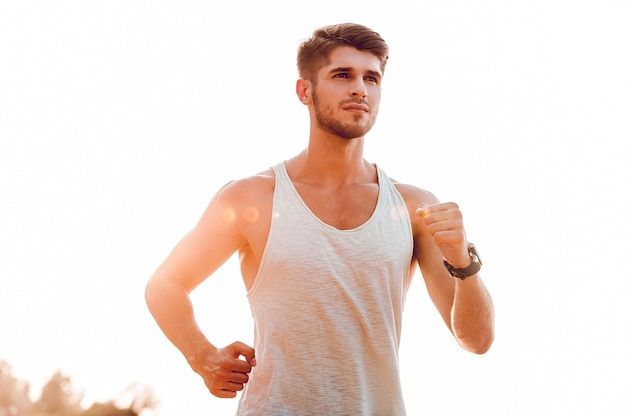 Garder son corps en forme et en bonne santé. Faible angle de vue du jeune homme musclé avec impatience en courant le long de la berge