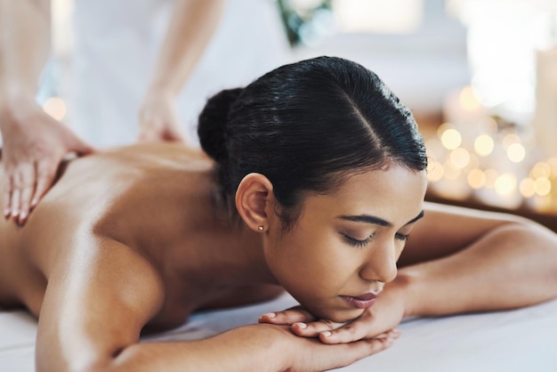 Gardez le dos droit Photo d'une jeune femme joyeuse et détendue se faisant masser à l'intérieur dans un spa