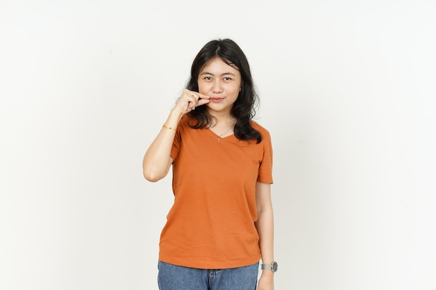 Gardez la lèvre secrète fermée de la belle femme asiatique portant un t-shirt orange isolé sur fond blanc