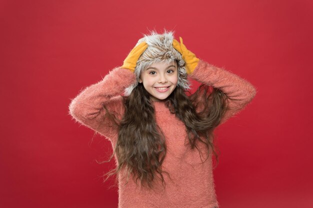 Gardez la tête dans l'activité de vacances au chaud en plein air petit enfant prêt pour l'hiver soins de santé saisonniers mode enfant vêtements chauds et conseils d'accessoires petite fille heureuse en chapeau à oreillette bonne fille toucher chapeau