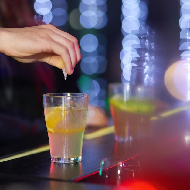 Gardez toujours les yeux sur votre boisson Gros plan d'un homme qui se drogue dans un verre dans une discothèque