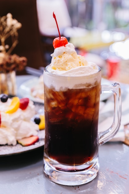 Garniture de Cerise Cola rafraîchissante et sucrée avec une boule de crème glacée à la vanille et de cerise fraîche.