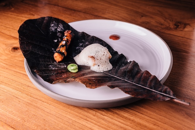 Garniture de poisson avec de la mousse sert de pois et de racine grillée avec du sel sur une feuille incendiée