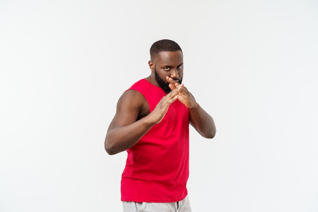 Un gars afro-américain adulte, drôle et ludique, debout de profil dans les arts martiaux pose avec les paumes levées, les sourcils froncés et le regard perdu.