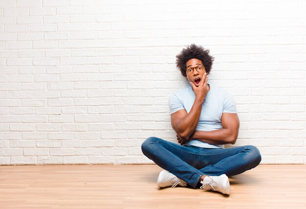 Photo un gars afro-américain assis bouche bée sous le choc et l'incrédulité